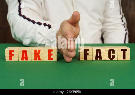 Geschäftskonzept. Ein Mann trennt die Würfel mit der Inschrift - GEFÄLSCHT oder FAKT Stockfoto