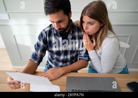 Junger weißer Mann, der sich wegen unbezahlter Rechnungen gestresst fühlt. Menschen, erste Wohnung, Hypotheken- und Schuldenkonzept Stockfoto