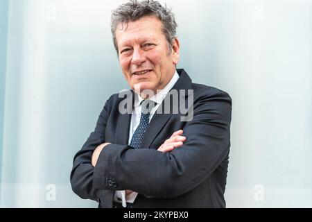 Porträt eines Geschäftsführers im Finanzbereich. Ein Unternehmer mit gekreuzten Armen, der gegen Buntglasfenster stand. Stockfoto