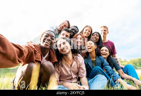 Eine junge afrikanische Frau macht ein Selfies seiner internationalen Freunde während eines Picknickens Stockfoto