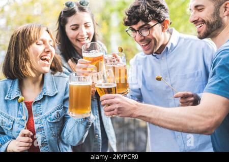 Eine Gruppe von Freunden trinkt Bier in der Brauereibar im Freien - glückliche, echte Freunde, die sich nach der Arbeit treffen Stockfoto