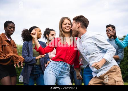 Seitlicher Blick auf eine Gruppe multiethnischer Freunde, die im Park zusammen tanzen Stockfoto