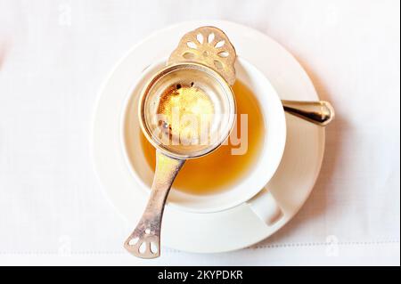 Eine Tasse frisch gereinigten Oolong-Tee, serviert auf einer weißen Tischdecke mit einem Silbersieb, Mandarin Oriental's Clipper Lounge, Hongkong. Stockfoto