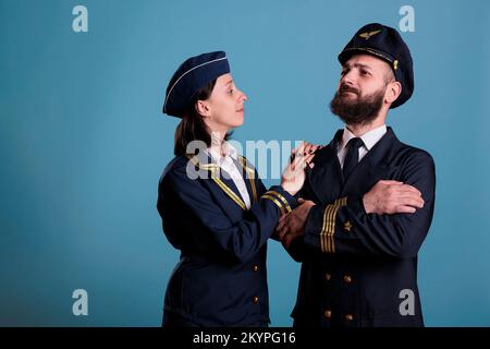 Selbstbewusster Flugzeugpilot und Flugbegleiter Paar in professioneller Uniform Porträt, Studio Medium Shot. Ernsthafte Flugzeugbesatzung, Flugzeugkapitän und Stewardess stehen, Flugzeugteam Stockfoto
