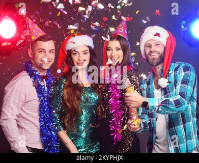 Freunde und der Weihnachtsmann feiern Weihnachten, haben Spaß und jagen einen Cracker vor dem Hintergrund des Fliegens in die Luft Stockfoto