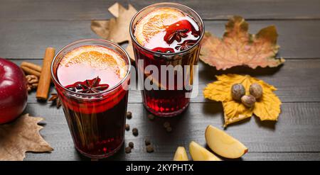 Gläser aromatischer Glühwein und Herbstblätter auf Holzhintergrund Stockfoto