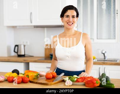 Lächelnde junge Hispanoamerikanerin, die Salat in der Küche zubereitete Stockfoto