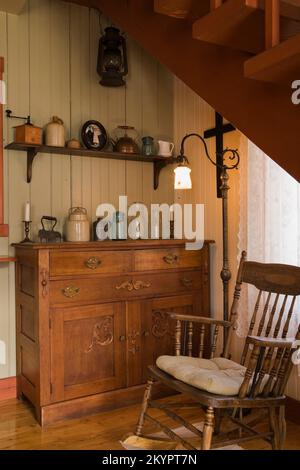 Antiker Schaukelstuhl und Kommode unter der Treppe im Speisesaal im alten, ca. 1825 Jahre alten Canadiana Cottage Stil Haus. Stockfoto