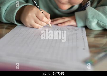 Mathematik Hausaufgaben.Hausaufgaben.Mathematikstunde.Student macht eine Mathematikaufgabe.Lernen und Bildung.Schulmädchen macht ihre Hausaufgaben. Bleistift in einer Kinderhand Stockfoto