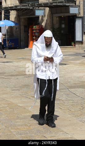 Ein religiöser Jude liest das Tikkun-Buch auf dem Weg zur Wailng-Mauer. Omar Ibn El-Khattab Sq. In der Nähe des Jaffa-Tors in der Altstadt von Jerusalem. Stockfoto