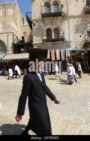 Ein orthodoxer jüdischer Mann, der durch den Omar Ibn El-Khattab Platz geht. In der Nähe des Jaffa-Tors in der Altstadt von Jerusalem. Stockfoto