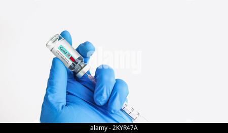 Ein Arzt füllt eine Spritze mit einem Covid-19- oder Coronavirus-Impfstoff aus einer Flasche, einem isolierten Objekt und einem horizontalen Kopierbereich auf weißem Hintergrund Stockfoto