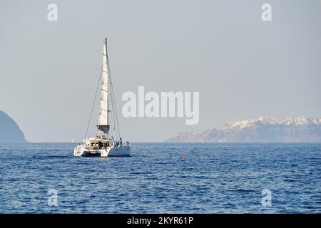 SANTORIN, GRIECHENLAND - 06. AUGUST 2015: Menschen auf einer Jacht nahe der Küste von Santorin. Santorini, klassisch Thera und offiziell Thira, ist eine Insel in der Stockfoto