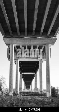 Unter Brücke. Betonbrückensäulen. Perspektivische Konstruktion unter der Brücke. Niemand, abstrakte Architektur, Foto in Schwarzweiß Stockfoto