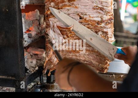 Taquero schneidet gespießtes Schweinefleisch für Tacos al Pastor in Mexico City Stockfoto