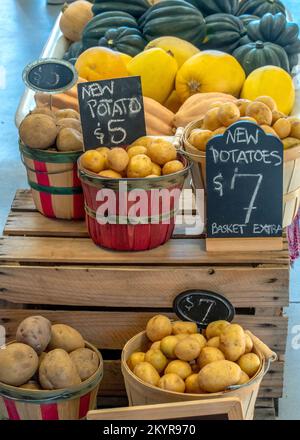 Marktausstellung von Frühkartoffeln in bunten Körben mit Kreidetafeln Stockfoto