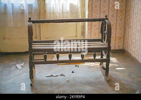 Altes Holzbett für kleine Kinder in einem verlassenen Haus Stockfoto