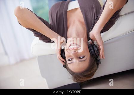 Ich genieße eine Musiktherapie. Eine glückliche junge Frau, die Musik über ihre Kopfhörer hört. Stockfoto