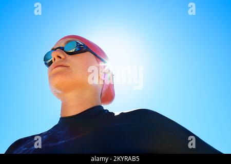 Training, um ein Lebensretter zu sein. Eine junge Frau, die im Winter am Strand in einem vollteiligen Neoprenanzug und Schwimmkleidung trainiert. Stockfoto