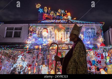 London, Großbritannien. 1.. Dezember 2022. Spektakuläre Weihnachtsbeleuchtung in Welling. Jonathan Blake (im Bild), ansässiger Erzbischof der Open Bischofskirche, hat seit 2002 jedes Jahr sein Familienhaus dekoriert. Für einige der lokalen Kinder ist das „Weihnachtshaus“, wie sie es nennen, ein wichtiger Teil ihres Weihnachtserlebnisses. Bischof Blake nutzt die jährliche Lichterausstellung, um Mittel für die Versorgung kleiner Dörfer in Gambia mit sauberem Wasser zu sammeln. Er hofft, dieses Jahr ein fünftes Dorf mit Wasser zu versorgen. Kredit: Guy Corbishley/Alamy Live News Stockfoto