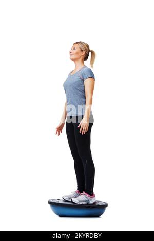 Ihre tägliche Übungsroutine. Eine schöne junge Frau, die beim Training auf einem bosu-Ball steht. Stockfoto