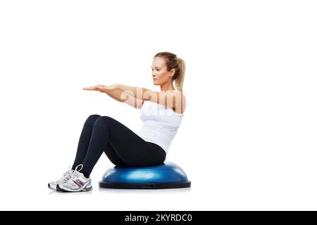 Sie ist in bester körperlicher Verfassung. Eine junge Frau, die beim Training auf einem bosu-Ball sitzt. Stockfoto