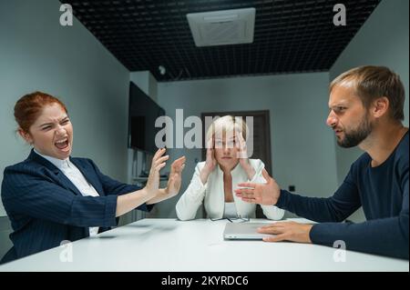 Blonde, rothaarige Frau und bärtiger Mann in Anzügen im Büro. Geschäftsleute fluchen während der Verhandlungen im Konferenzraum. Stockfoto