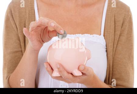 Finanzstabilität gibt Sicherheit. Eine junge Frau, die eine Münze in ihr Huckepack steckt. Stockfoto