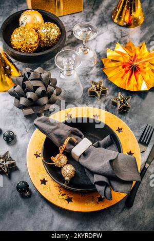 Glamouröses schwarz-goldenes Ambiente mit modernen Tellern für Silvester und Weihnachten Stockfoto