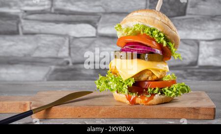 Frischer, leckerer Hähnchenburger auf dem Holztisch Stockfoto
