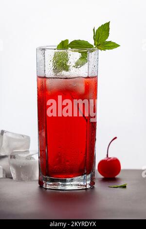 Ein Glas mit einem roten Getränk explodiert mit Spritzern auf grauem Hintergrund Stockfoto