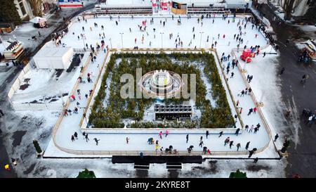 Menschen, die auf einer wunderschönen Eislaufbahn in Open Air dekorierten Weihnachtsbeleuchtung, Dekoration, leuchtenden Girlanden am Wintertag Schlittschuhlaufen. Weihnachtsfeierlichkeiten im neuen Jahr. Luftaufnahme Stockfoto