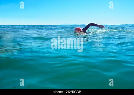 Trainiere, wo immer es Wasser gibt. Ein Schwimmer im offenen Meer. Stockfoto