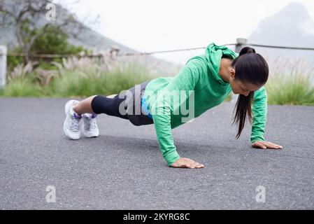 Aufwärmen vor dem Lauf. Eine junge Frau, die vor dem Laufen Pressen macht. Stockfoto