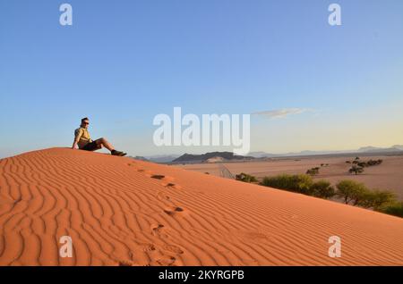 Mann sitzt auf der Düne in der Trockenpfanne des Sossusvlei Namib Naukluft Nationalparks Stockfoto