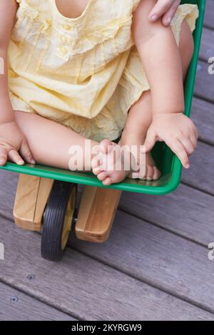 Gib mir mehr Druck, Mom. Zugeschnittenes Bild eines kleinen Mädchens, das in einem Spielzeugwagen geschoben wird. Stockfoto