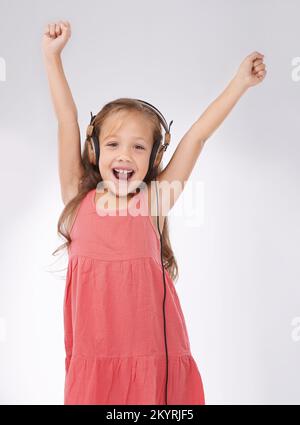 Sie ist ein sehr musikalisches Kind. Studioaufnahme eines kleinen Kindes, das Musik auf einigen Kopfhörern hört. Stockfoto