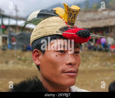 Raga, Arunachal Pradesh, Indien - 02 25 2009 : Porträt eines jungen Nyishi-Stammesmannes, der traditionelle Kopfbedeckungen mit Hornschnabel und Federn trägt Stockfoto