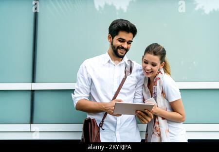 Glückliche junge Geschäftsleute, die im Freien chatten und digitale Geräte nutzen Stockfoto