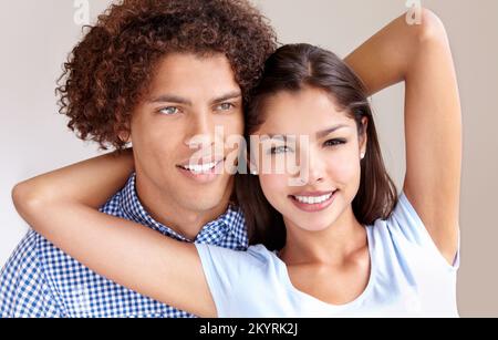 Junge Liebe. Studiofoto eines glücklichen, jungen ethnischen Paares, das sich festhält und lächelt. Stockfoto