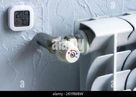 Heizkörper mit Temperaturregler. Ein Thermometer, das Grad und Feuchtigkeit in der Wohnung anzeigt. Wintergasheizung. Stockfoto