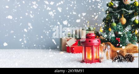 Weihnachtskerzen und Geschenk mit Anhängern zum Schreiben. Im Hintergrund befinden sich ein Weihnachtsbaum und Geschenke mit Lichtern. Neujahrshintergrund. Stockfoto