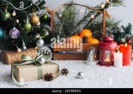 Weihnachtsgeschenk mit Anhängern zum Schreiben. Im Hintergrund befinden sich ein Weihnachtsbaum und Geschenke mit Lichtern. Neujahrshintergrund. Stockfoto