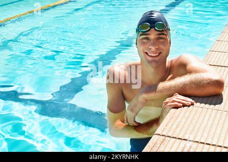 Es ist der beste Weg, um fit zu werden. Schöner männlicher Schwimmer, der lächelt, während er sich an der Seite des Pools ausruht. Stockfoto