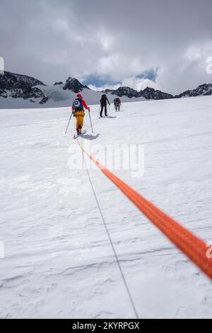 Tour in großer Höhe, Skitouristen, die an einem Seil über den Alpeiner Ferner Gletscher laufen, Winter in den Bergen, Neustift im Stubai-Tal, Tirol, Österreich, EU Stockfoto