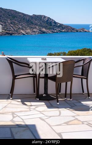 Tolle Aussicht von einem Balkon mit Stühlen und einem Tisch mit Blick auf den berühmten Mylopotas Strand in iOS Griechenland Stockfoto