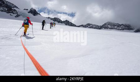 Tour in großer Höhe, Skitouristen, die an einem Seil über den Alpeiner Ferner Gletscher laufen, Winter in den Bergen, Neustift im Stubai-Tal, Tirol, Österreich, EU Stockfoto