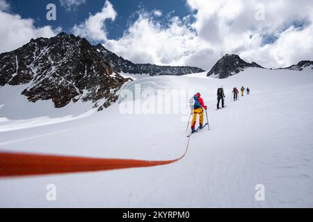 Tour in großer Höhe, Skitouristen, die an einem Seil über den Alpeiner Ferner Gletscher laufen, Winter in den Bergen, Neustift im Stubai-Tal, Tirol, Österreich, EU Stockfoto