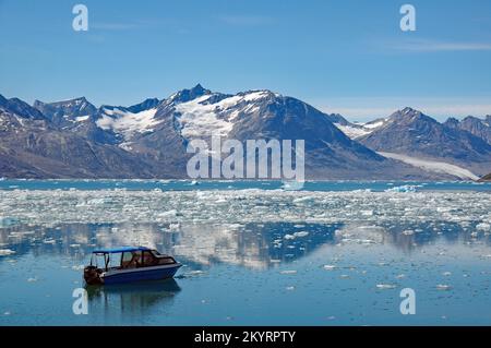 Eisberge in einem Fjord, kleines blaues Boot, Stille, Ruhe, karge Landschaft, Schlittenhund, Eisfjord, Ostgrönland, Nordamerika, Knud Ra Stockfoto