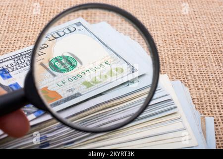 Lupe wird über die Banknote Bündel von US-Dollar gehalten. Stockfoto